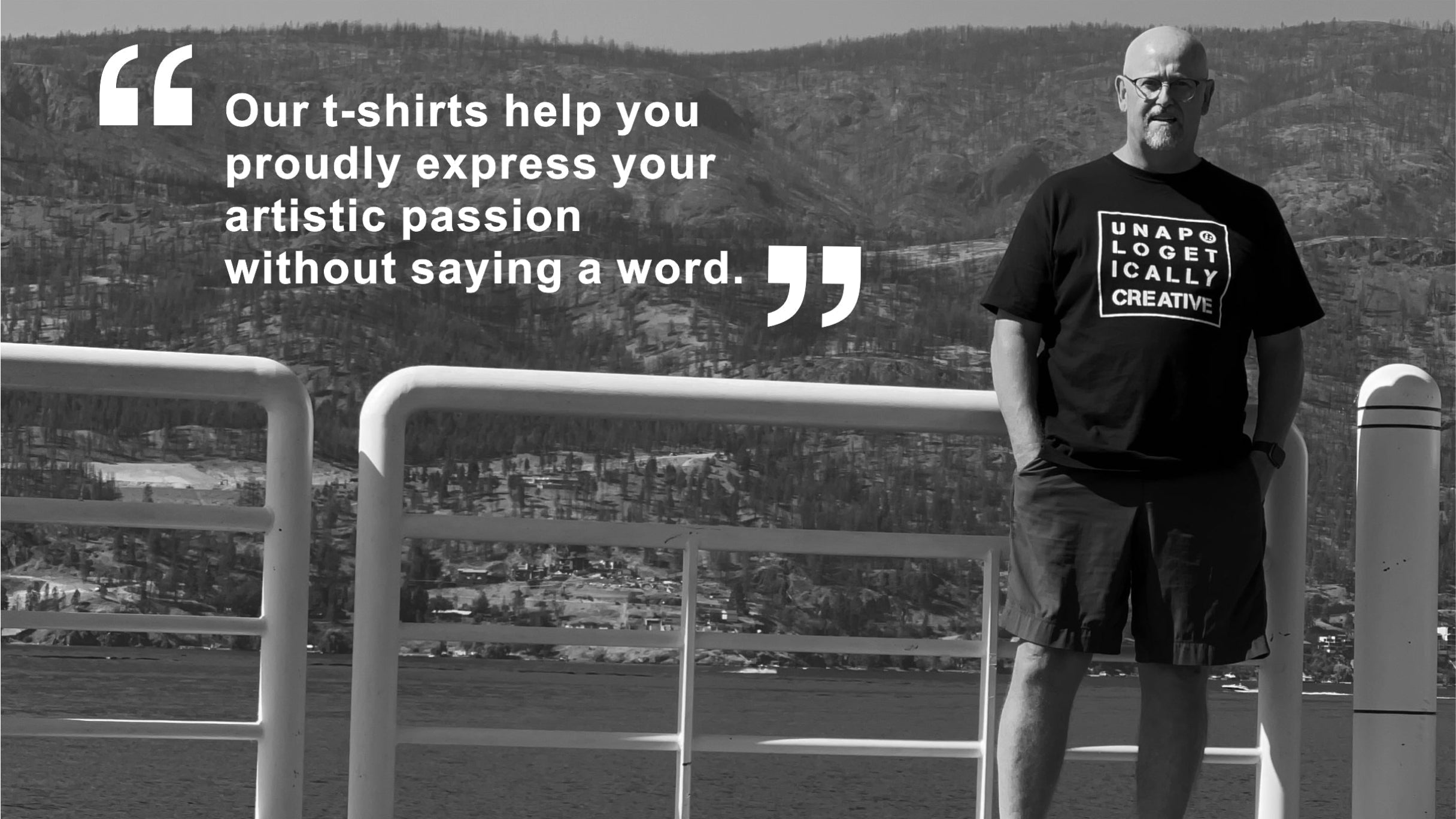Man wearing a t-shirt with text, standing by a railing with scenic background